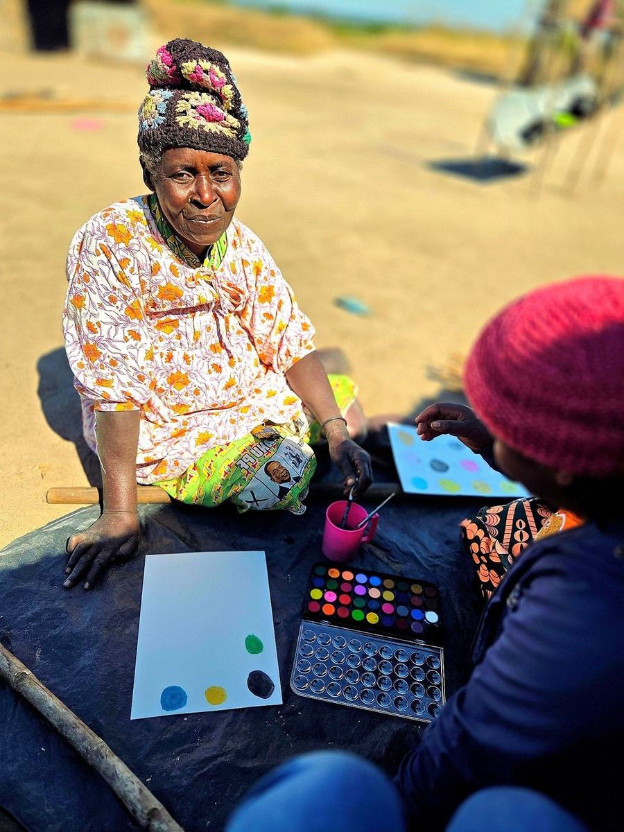 With the team's support, a woman tries painting for the first time and asks to do it again.